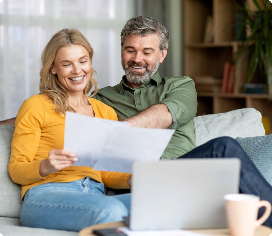 Happy couple with laptop and paperwork